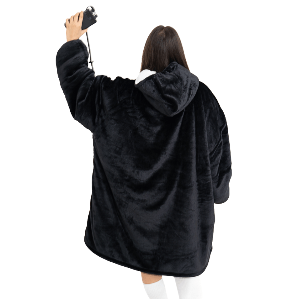 Eine Person, die ein Schwarzes Wunder Hoti von The Hoti trägt, steht mit dem Rücken zur Kamera und hält in der erhobenen Hand eine Tasse mit Riemen. Sie trägt kniehohe weiße Socken vor einem schlichten weißen Hintergrund.