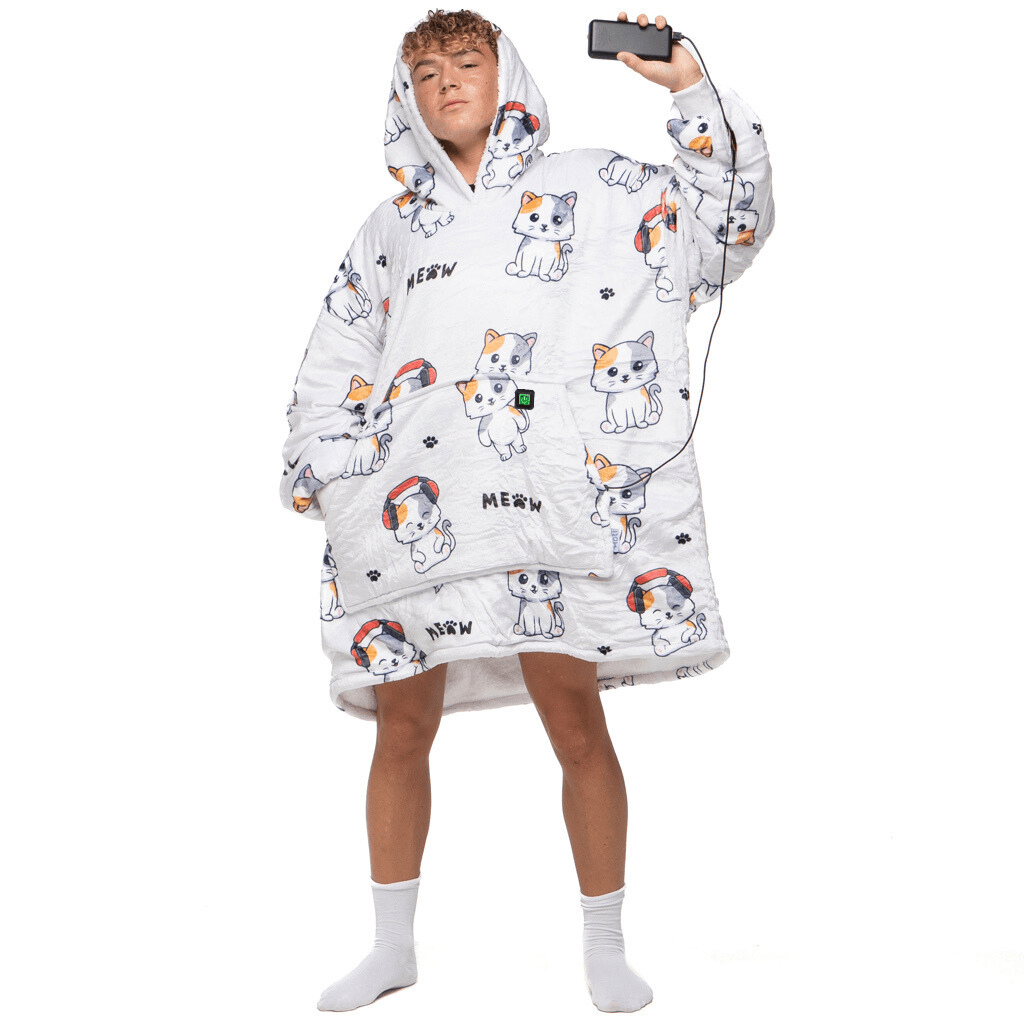 Eine Person trägt eine Träumende Katze Hoti von The Hoti, eine übergroße Kapuzendecke mit Katzenmuster, und hält ein eingestecktes Mobiltelefon in der Hand. Sie steht auf einem weißen Hintergrund und trägt weiße Socken.